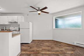 an empty room with a kitchen and a ceiling fan