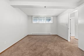 a spacious living room with carpet and a window