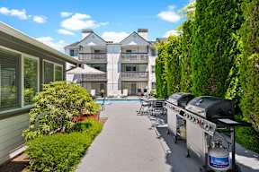 a patio with a grill and a pool in front of a house