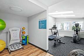 a gym with a treadmill and weights on the floor and a window