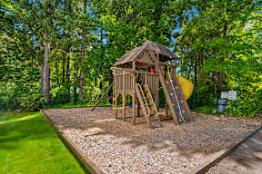 a swing set in a backyard with trees and a yellow slide