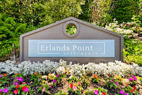 a sign that says rentals point apartments in a garden with flowers