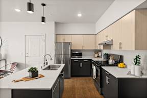 an open kitchen with white counter tops and black appliances and at Telka Apartments, Washington, 98383
