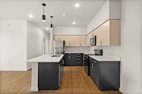 A modern kitchen with black cabinets and a white island.