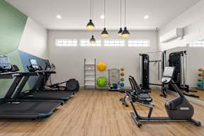 a gym with treadmills and weights on a wooden floor at Telka Apartments, Silverdale, WA, 98383