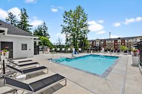 A swimming pool with sun loungers and a building in the background.