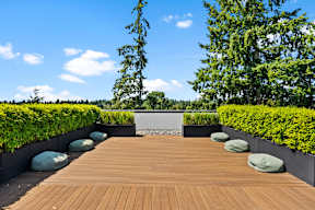 A wooden deck with green plants on the sides.