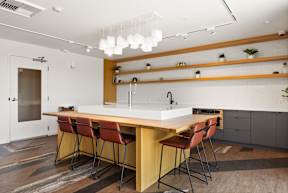 A modern kitchen with a long wooden table and red chairs.