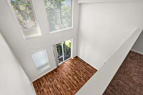 A room with a wooden floor and a white wall with a window.