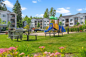 A playground with a slide and a picnic table in the foreground.