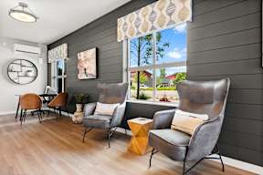 A living room with grey chairs and a wooden floor.