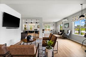 A living room with a brown couch and a television on the wall.