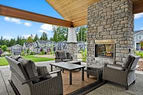 A patio with a stone fireplace and wicker furniture.