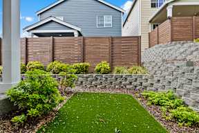 A backyard with a green lawn and a stone wall.