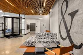 A modern office lobby with a large ampersand on the wall.