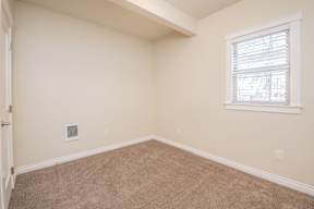 A room with a window and carpeted floor.