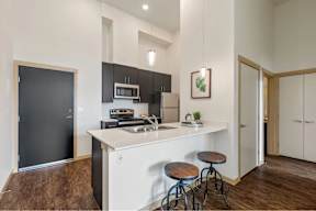 A kitchen with a white countertop and a black refrigerator.