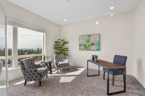 A room with a table and chairs and a painting on the wall.
