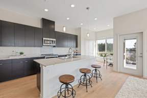 A kitchen with a white island and black cabinets.