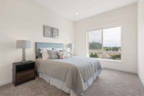 A bedroom with a bed, nightstand, and window.