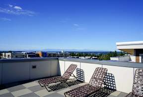 Three chairs are on a patio overlooking a city.