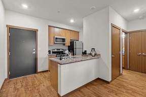 A kitchen with wooden cabinets and a black door.