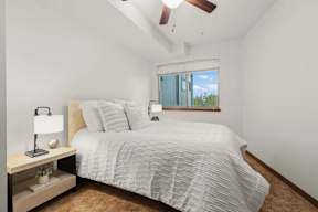 A bedroom with a bed, nightstand, and window.