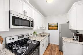 A kitchen with a stove, microwave, and refrigerator.