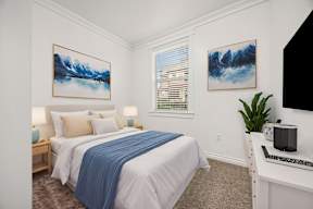 A bedroom with a bed, nightstands, and two paintings on the wall.