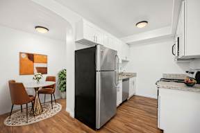 A kitchen with a black refrigerator and white cabinets.
