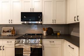 A modern kitchen with white cabinets and a black stove top.