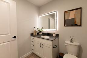 A bathroom with a white toilet and a mirror above a sink.