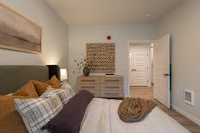 A bedroom with a bed, nightstand, and a painting on the wall.