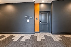 A hallway with a black door and a brown door.