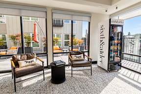 A room with a sofa, chair and a trash bin in front of a window with a sign that says "sixth&kalker".