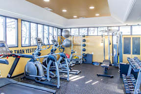 A gym with a variety of equipment including treadmills, weights, and exercise machines.