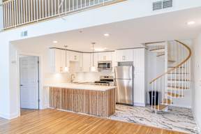 A modern kitchen with a wooden floor and stainless steel appliances.