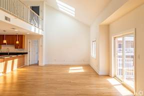A spacious, empty room with wooden floors and a skylight.