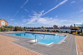 A large outdoor swimming pool with a tiled edge and a diving board.