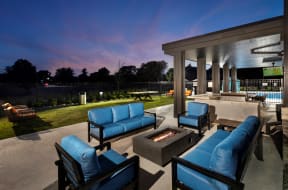 a patio with blue couches and a fire pit