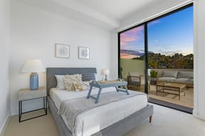 a bedroom with a bed and a sliding glass door to a balcony