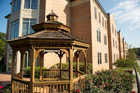 A gazebo sits in front of a brick building.