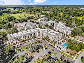 Aerial view of The Flats at Tioga Town Center apartments in Newberry, FL with parking, landscaped grounds, and pool.