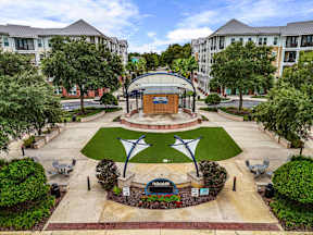 Central courtyard with stage, lawn and shaded seating near The Flats at Tioga Town Center apartments in Newberry, FL.