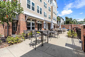 Outdoor patio with tables, umbrellas and grilling area at The Flats at Tioga Town Center apartments in Newberry, FL.