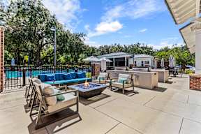 Outdoor lounge with fire pit, grilling stations, and pool at The Flats at Tioga Town Center apartments in Newberry, FL.
