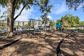 Playground with swings and bench at The Flats at Tioga Town Center apartments in Newberry, FL.