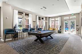 Game room with pool table, bar-height seating, and patio doors at apartments in Newberry, FL.