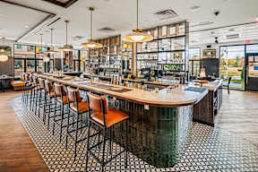 A bar with a long wooden counter and chairs.
