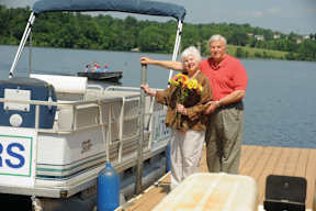 A man and woman stand on a dock next to a boat with the letters "RS" on it.
